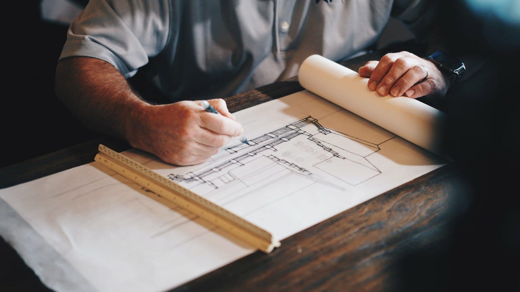 An architect sitting at a table drafting a building concept.