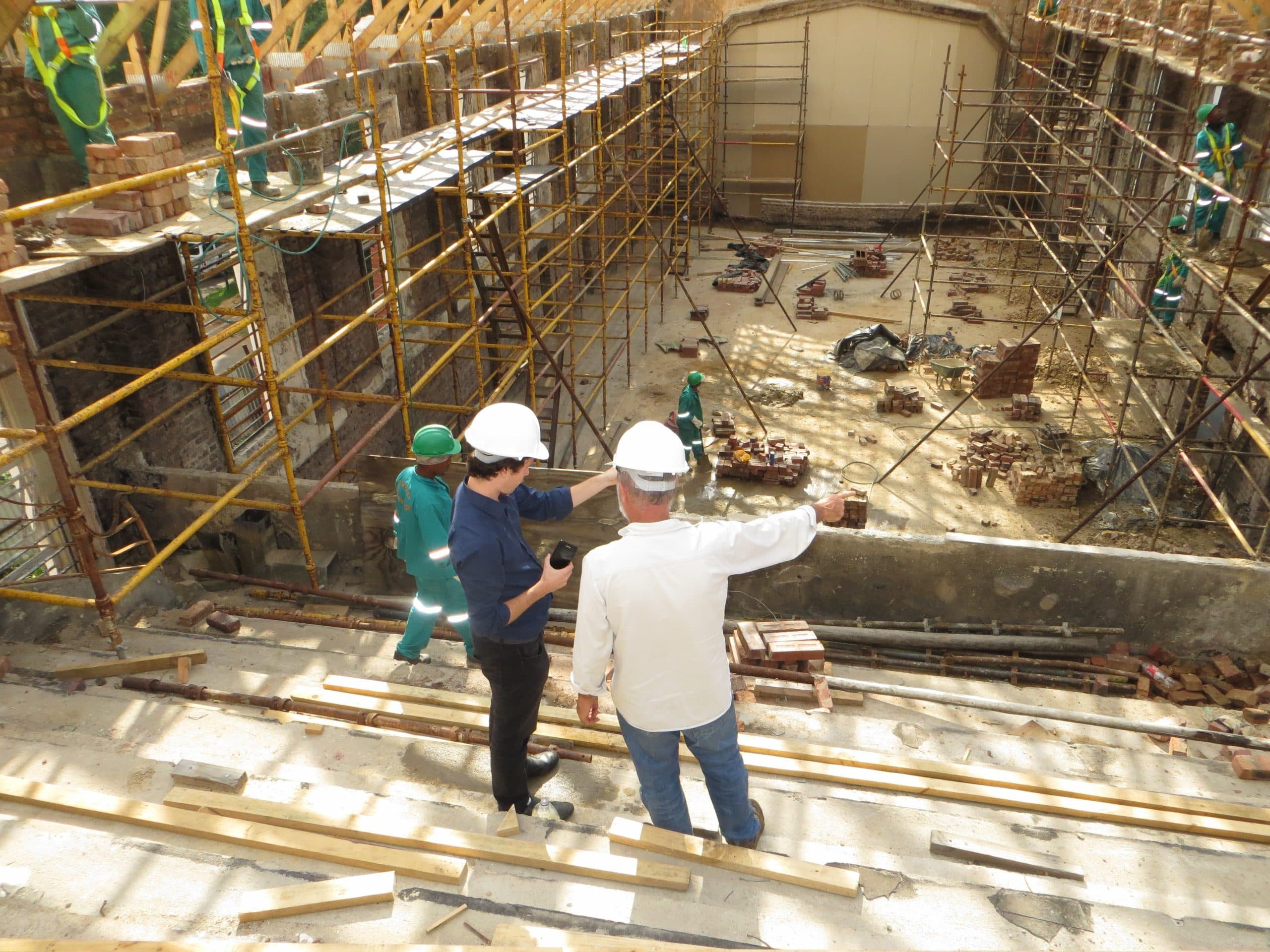 A construction site with a scaffold and two managers pointing.